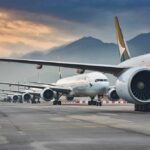 Commercial airliners lined up on an airport taxiway at dusk