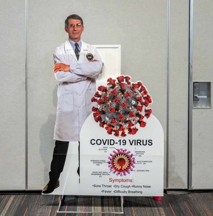 shutterstock_1949881045 Cardboard cutout of doctor with COVID-19 virus info display