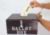 Hand in handcuffs casting a vote into a ballot box