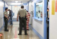 Corrections officers escort an inmate in a jail hallway