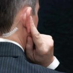 Man in suit with earpiece touching his ear