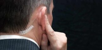 Man in suit with earpiece touching his ear