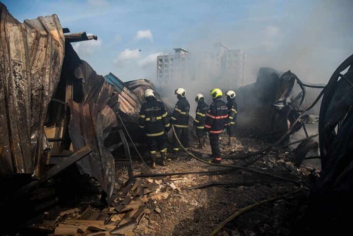Firefighters amid twisted metal and smoke at a disaster site