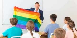 Teacher holding a rainbow pride flag in front of students