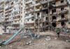 Damaged apartment building behind a playground slide