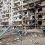 Damaged apartment building behind a playground slide