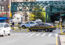 Police cars block a city intersection with yellow crime scene tape