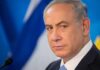 Netanyahu Axes Tour – What’s He Dodging? man in suit at podium