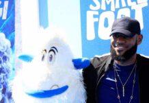 LeBron James posing next to a white yeti mascot at a blue-themed event