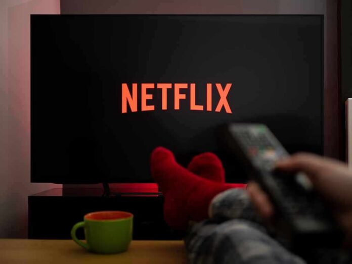 TV screen with Netflix logo and person holding remote