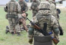 Peace Play From Strength Jolts Washington Soldier in camouflage with rifle and body armor stands near a group in a field