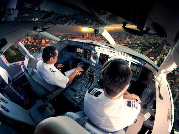 Pilots in an airplane cockpit during city approach at sunset