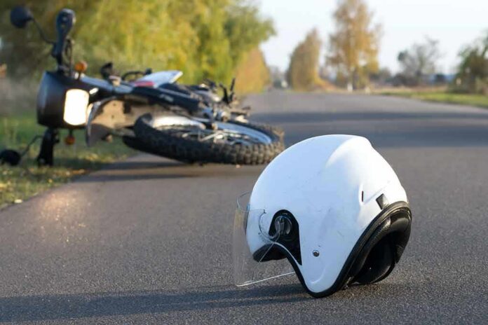 White motorcycle helmet on road with fallen bike in background